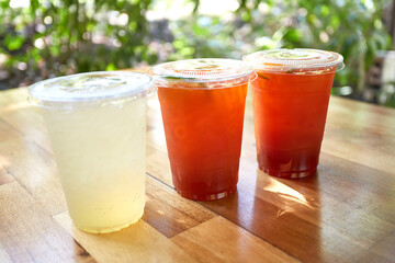 Iced lemon tea and honey lemon soda in plastic cups with lids placed on wooden tables, Thai herbal...