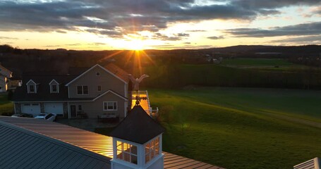Colorful starburst sunset with bald eagle rooftop ornament. Rural countryside view in America. USA theme nature meadow pasture valley view. - Powered by Adobe