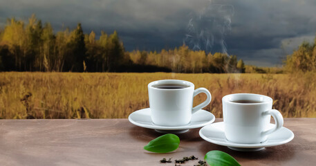 two cups of white tea on a wooden table against the backdrop of an autumn landscape, tea drinking in nature
