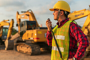 Asian engineers use walky talky with team for earthmoving project by excavator. foreman use laptop...