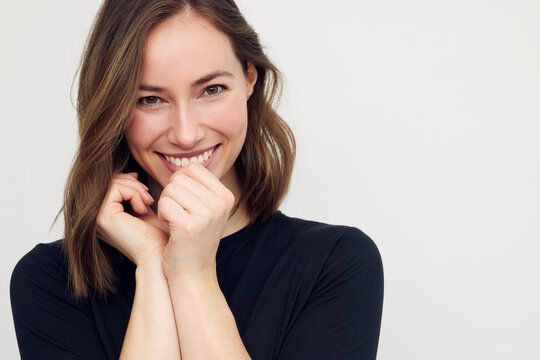 Portrait of beautiful young female or woman looking happy and confident in camera. Big smile on her face, looking beautiful standing isolated on white background. Concept: having a secret. 