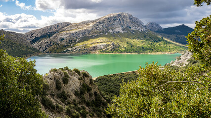 Wide Panorama of artificial lake embassament de cúber at springtime with calm turquoise water...