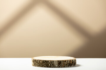 Wood slice podium on a beige background with shadows. Natural cosmetics and beauty concept