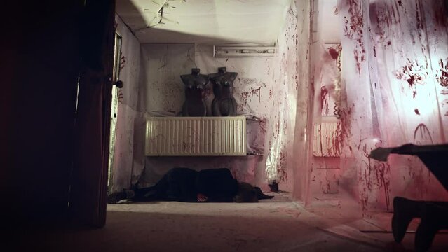 Psychopath maniac in a clown costume and his victim. The female body lies in a scary room with bloody streaks.