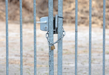 Large metal fence locked with a padlock and a chain