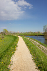 Beautiful bike path along the river. White gravel path with grassy edges. Cordignano, Italy. Vertical image.