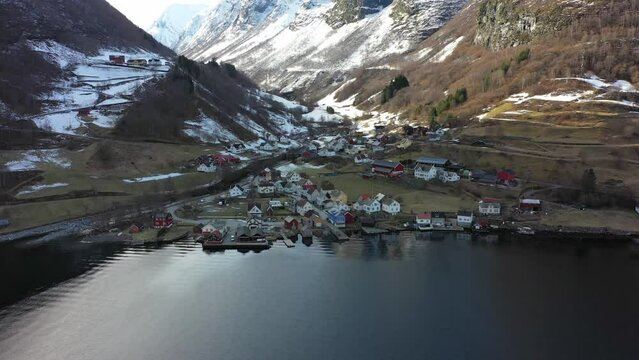 Beautiful aerial overview of Undredal village by the sea during winter - Snowy undredal valley with sunlight in background