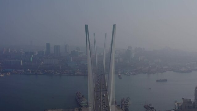 Golden cable bridge. Vladivostok city. Aerial shooting. The drone flies over the bridge. In the distance, cars drive over the bridge.
