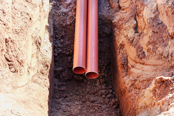 Orange sewer pipes in a trench. Laying communications in the ground during the construction of the...