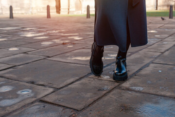 feet of a woman in a black shoes  on the city street on cold day