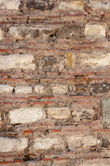 Old wall of rows of large blocks and rows of small bricks. Vertical photo.