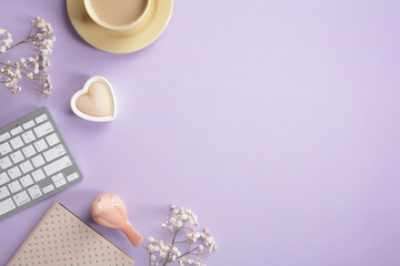 Flat lay, top view cute office table desk. Feminine workspace with keyboard, coffee cup, notebook, heart shaped candle, bird, flowers on pastel purple background.