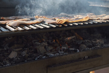 A man cooking bacon on barbecue grill. BBQ smoke. Food background. Detail of the flames.