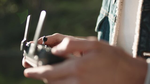 Hand of a Drone Operator man while pilot a quadcopter remote controller.