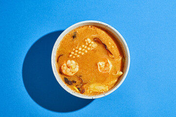 Obraz na płótnie Canvas Ramen soup with shrimp, squid in a plate on a blue background