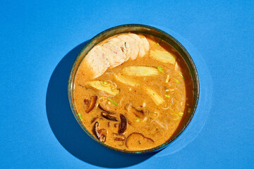 Ramen soup with chicken, shiitake mushrooms in a plate on a blue background