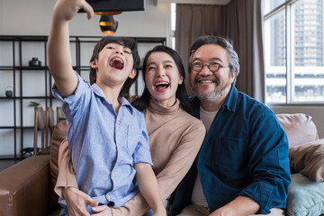 Obraz premium Family smiling at camera. Happy family taking a selfie, smiling at a phone at home