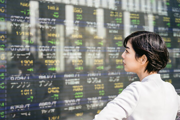 株価ボードを見る女性
