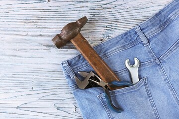 Dad tools in jeans pocket on a wooden background, top view, concept of congratulations on Father's Day, save space, postcard