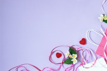 Bouquets of fresh jasmine flowers, packages, hearts and pink ribbons on a lilac background, top view, flatly, copy space