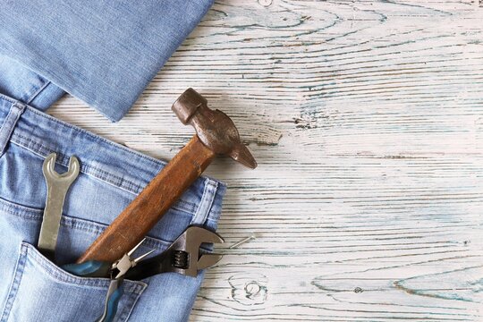 Dad tools in jeans pocket on a wooden background, top view, concept of congratulations on Father's Day, save space, postcard