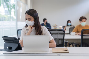 Asian creative business team working after lockdown with protective prevention face mask.