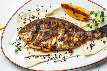 Plate with prepared dorado fish, Whole Bbq sea bream baked. Dorado grill. Ketogenic, keto or paleo...