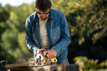 Craftsman working with circular saw at construction site