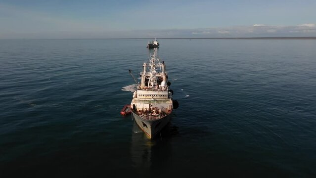 Fishing boats are sailing on the sea. The fishing vessel approaches the fish processing vessel to transfer the caught fish.