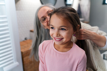 Fototapeta premium Senior grandmother and granddaughter standing indoors in bathroom, daily routine concept.