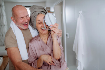 Senior couple in love in bathroom, looking at mirror and smiling, morning routine concept.