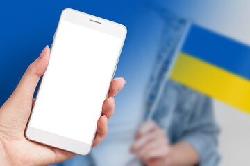 Ukrainian news channel. Female hand holds a mobile phone with a blank white screen and female hands hold a small ukrainian flag isolated over blue background