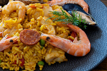 view of a paella with prawns, lemon, clams on a plate