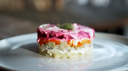 Traditional Russian salad with beetroot and herring vegetables, lying on a wooden table in a white plate