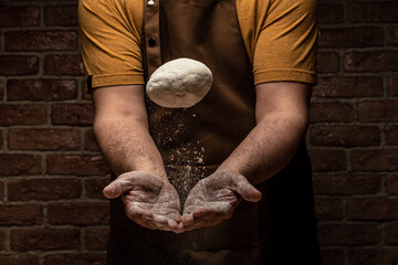 White flour flying into air as pastry chef in white suit slams ball dough on white powder covered...