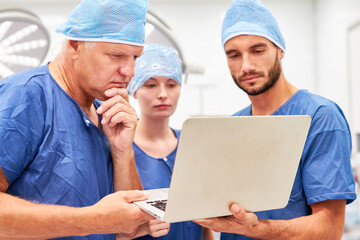 Doctors on surgery team look at laptop together