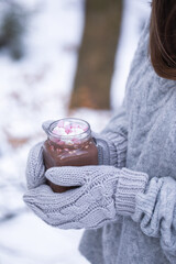 A woman holding hot cocoa with marshmallows in winter