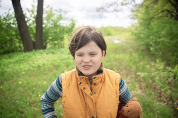 Teenage girl in a yellow warm vest with a soft teddy bear walking in nature