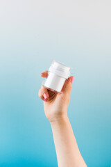 A mock-up of a jar of moisturizer in a woman's hand on a blue background.