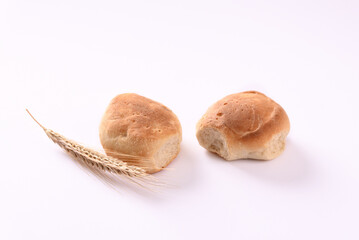 Freshly baked buns and ears of wheat on white background.