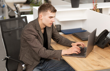 young cheerful programmer working in office on laptop
