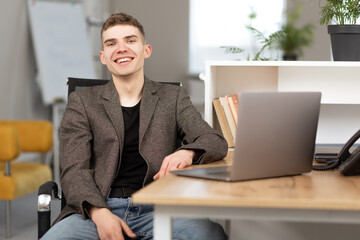 young cheerful programmer working in office on laptop