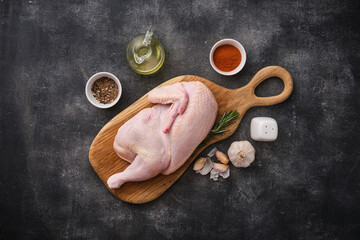 Presented on a wooden board is a half-cooked raw chicken with spices and seasonings.