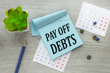 pay off debt. text on a blue sticker on a torn calendar.