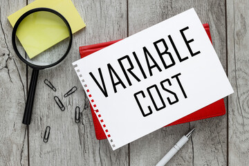 Variable Cost. sheet of paper with text on a red notepad