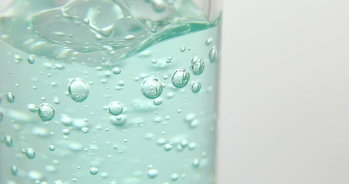 Close up of blue serum poured in a medical glass bottle, isolated on a white background, natural essential oil, cosmetic, medicine.