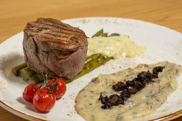 Grilled beef steak served on a plate with asparagus and mushroom sauce