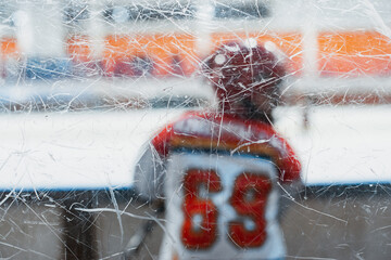 Children's ice hockey. A child hockey player in a protective uniform on the glass side of the ice field.