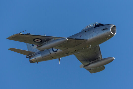Albion Park, Australia - May 4, 2014: Former Royal Australian Air Force (RAAF) Commonwealth Aircraft Corporation CA-27 (North American F-86) Sabre jet aircraft flying against a blue sky. .