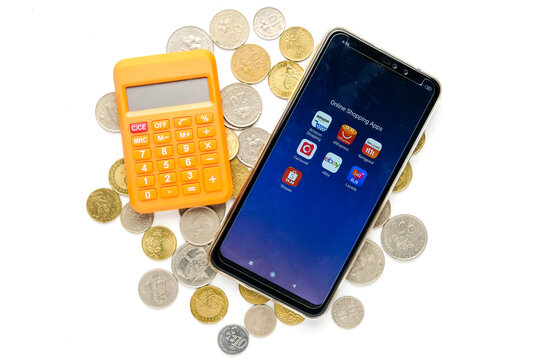 A flatlay picture of smartphone with variety Online Shopping Apps and calculator on coins. Trend online shopping has increase during covid-19 pandemic.